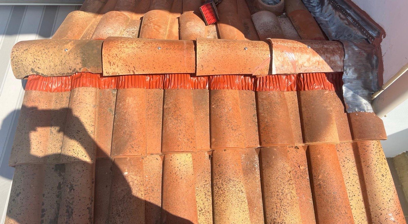 Faîtage de toiture avec closoir rouge et raccord zinc contre mur